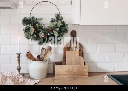 Closeup of kitchen interior. Christmas decoration. Advent floral hoop wreath hanging on peg rails. White brick wall, metro tiles, wooden countertops Stock Photo