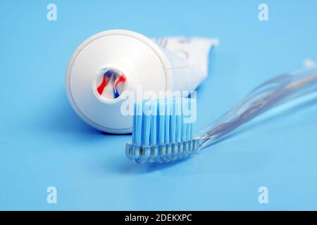 toothbrush with tricolor toothpaste on it and white toothpaste tube on blue background Stock Photo