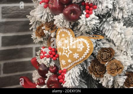 Christmas decoration with gingerbread heart, red berries hanging on white fir. Christmas background Stock Photo