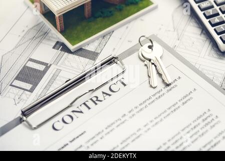 A mortgage loan contract agreement paper with house keys and floor plan on a table being prepared for a new home owner or real estate project develope Stock Photo