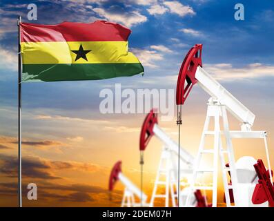 Oil rigs against the backdrop of the colorful sky and a flagpole with the flag of Ghana. The concept of oil production, minerals, development of new d Stock Photo