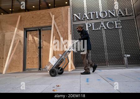 Washington, USA. 19th Nov, 2020. A delivery worker walks past an office building boarded up with plywood in Washington, DC, the United States, Nov. 19, 2020. TO GO WITH XINHUA HEADLINES OF DEC. 1, 2020 Credit: Liu Jie/Xinhua/Alamy Live News Stock Photo