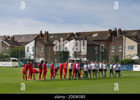The two teams line up on the pitch at Marine Football Club (in white), pictured before they played host to Ilkeston FC in a Northern Premier League premier division match. The match was won by the home side by 3 goals to 1 and was watched by a crowd of 398. Marine are based in Crosby, Merseyside and have played at Rossett Park since 1903, the club having been formed in 1894. Stock Photo