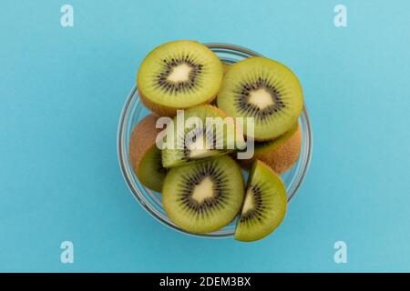 High angle view of bowl of freshly cut kiwi on blue background Stock Photo