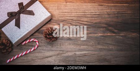 Silver shiny Christmas present and candy cane on wood. Stock Photo