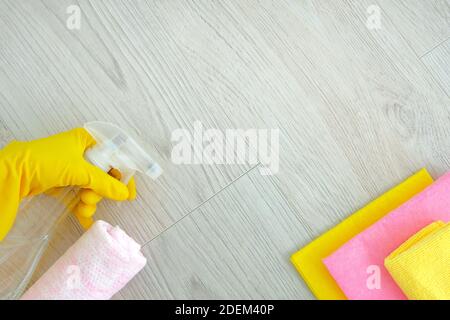 Pink cleaning tools: rags, sponges, detergent liquid, hands in rubber gloves on light wooden background. Detergents and cleaning accessories. Top view Stock Photo