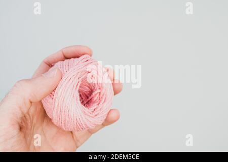 A closeup shot of a hand holding a pink yarn ball for knitting Stock Photo