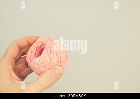 A closeup shot of a hand holding a pink yarn ball for knitting Stock Photo