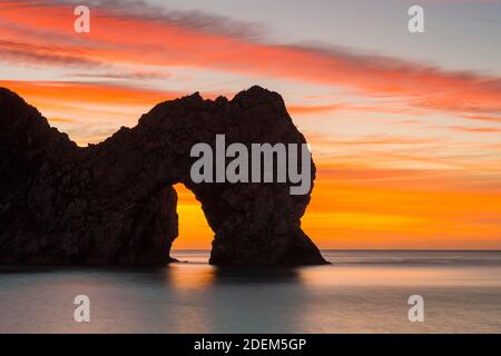 Durdle Door, Dorset, UK.  1st December 2020.  A spectacular sunrise with the clouds glowing red above Durdle Door on the Dorset Jurassic Coast on the first day of winter.  Picture Credit: Graham Hunt/Alamy Live News Stock Photo
