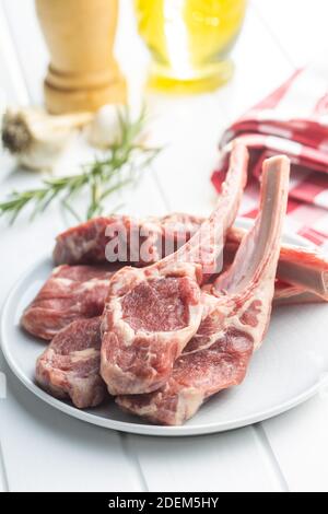 Slices raw lamb chops on plate on white table. Stock Photo