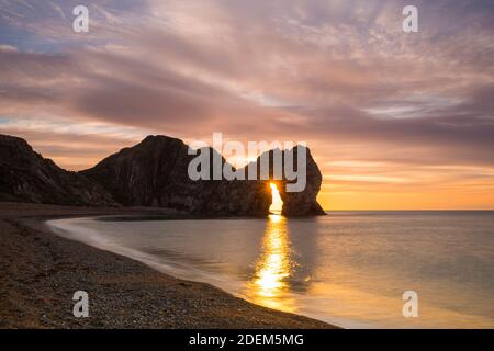 Durdle Door, Dorset, UK.  1st December 2020.  A spectacular sunrise through the keyhole at the sea arch of Durdle Door on the Dorset Jurassic Coast on the first day of winter.  Picture Credit: Graham Hunt/Alamy Live News Stock Photo