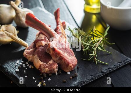 Slices raw lamb chops on black table. Stock Photo