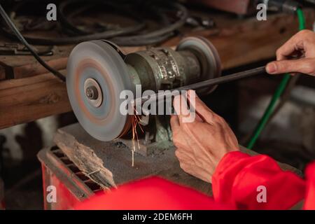 close up of mechanical hands using a grinding machine to smooth the ends of the bolts when in the garage Stock Photo