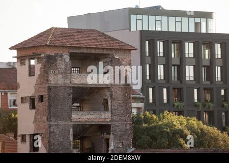 Old industrial factory building being destroyed while a modern residential skyscraper high rise is under construction in background in Belgrade, Serbi Stock Photo