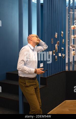 young bald man using smartphone and smiling. Looking up. Stock Photo