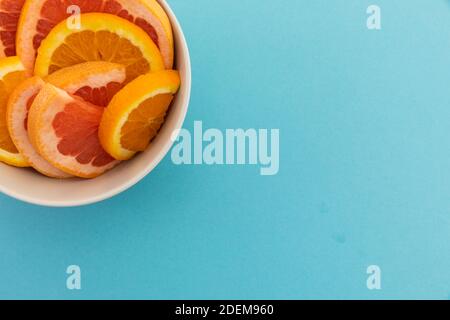 High angle view of bowl of freshly cut orange slices on blue background Stock Photo