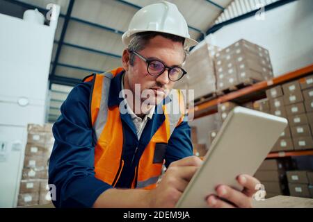 Portrait of a male warehouse worker looking at digital tablet screen in industrial warehouse Stock Photo