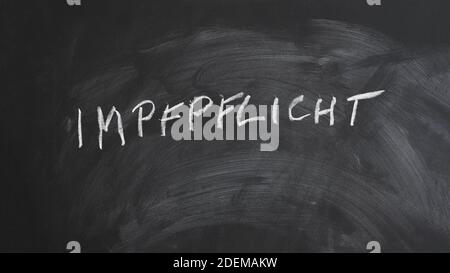 Impfpflicht translates as compulsory or mandatory vaccination in German language - text written in chalk on blackboard Stock Photo