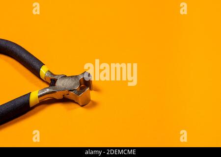 The construction tool ticks metal steel with a black handle on an orange background. For snacking wire, small size Stock Photo