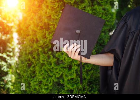 Successful graduate, in academic dresses, raised up graduation cap, farewell study, can be used for advertising, Stock Photo