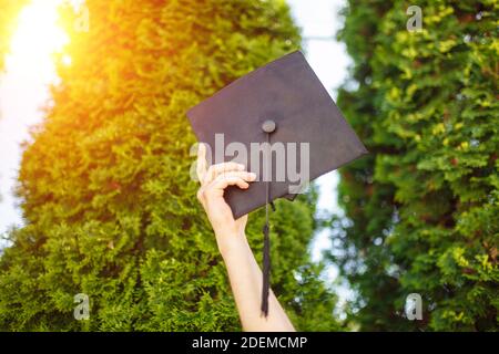 Successful graduate, in academic dresses, raised up graduation cap, farewell study, can be used for advertising, Stock Photo