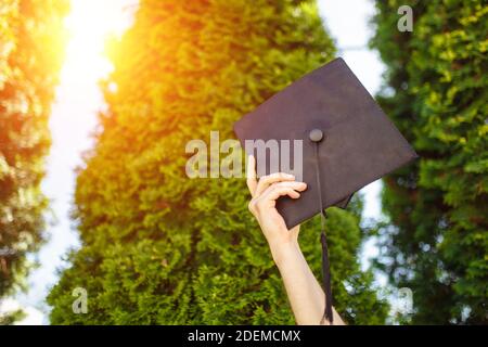 Successful graduate, in academic dresses, raised up graduation cap, farewell study, can be used for advertising, Stock Photo