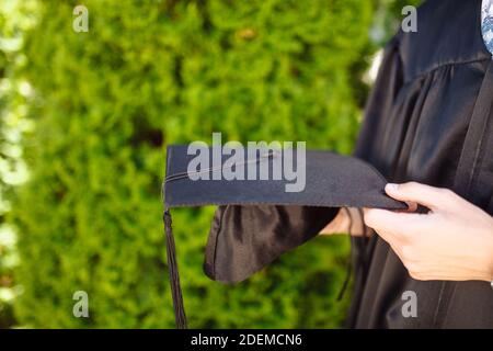 Successful graduate, in academic dresses, holding a graduation cap farewell study, can be used for advertising, Stock Photo