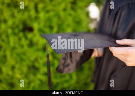 Successful graduate, in academic dresses, holding a graduation cap farewell study, can be used for advertising, Stock Photo