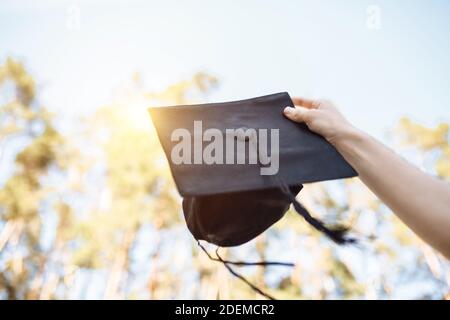 Successful graduate, in academic dresses, raised up graduation cap, farewell study, can be used for advertising, Stock Photo