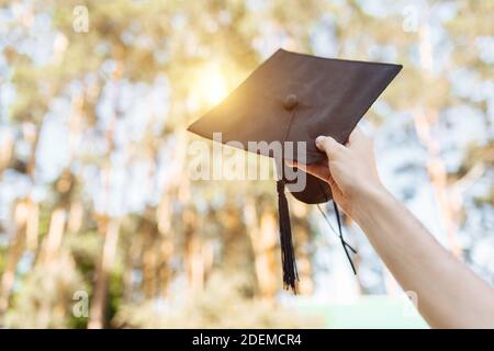 Successful graduate, in academic dresses, raised up graduation cap, farewell study, can be used for advertising, Stock Photo