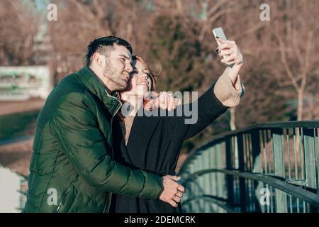 Cheerful Young Couple Making Selfie on the Bridge. Two Happy People Love Story on the Street Stock Photo