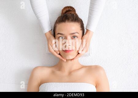 Pretty young woman relaxing during face lifting massage, top view Stock Photo
