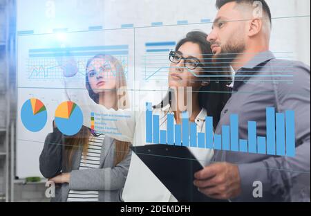 Business People Analyzing Corporate Data, Looking At Financial Infographic On Digital Panel Stock Photo