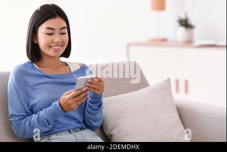 Smiling asian woman using smartphone at her home Stock Photo
