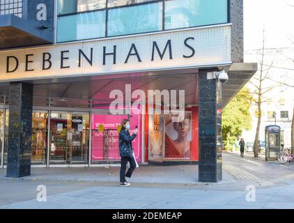 A woman wearing a protective face mask walks past Debenhams department store on Oxford Street, London. Many businesses are in financial trouble and have announced closures as the coronavirus pandemic takes its toll on the economy. Stock Photo