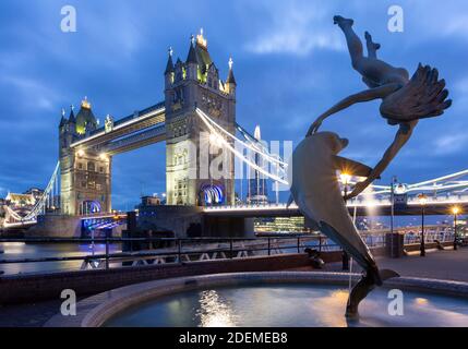 Girl with a Dolphin Fountain sculpture and Tower Bridge in background, London, March 2020 Stock Photo