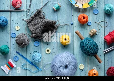 Wool bundles, yarn balls, cord. Crochet and knitting needles on light mint blue wood. Stock Photo