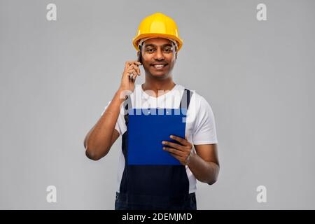 indian builder with clipboard calling on cellphone Stock Photo
