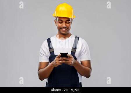 happy indian or builder in helmet using smartphone Stock Photo