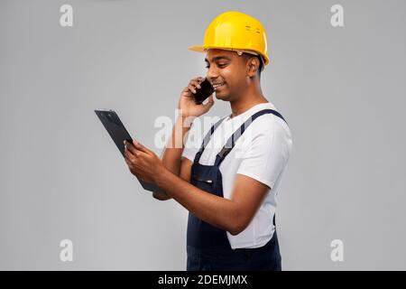indian builder with clipboard calling on cellphone Stock Photo