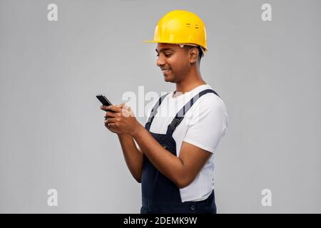 happy indian or builder in helmet using smartphone Stock Photo