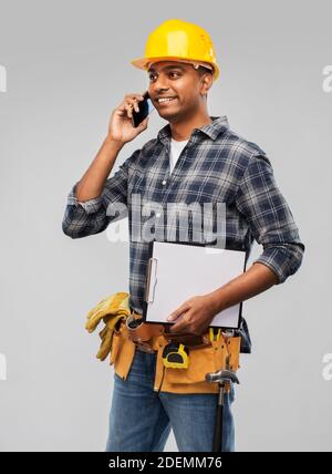 indian builder in helmet calling on smartphone Stock Photo