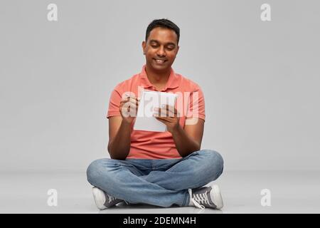 indian man in polo shirt writing to notebook Stock Photo