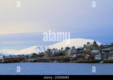 Small scottish town in winter scene with houses and big hill covered with snow Stock Photo