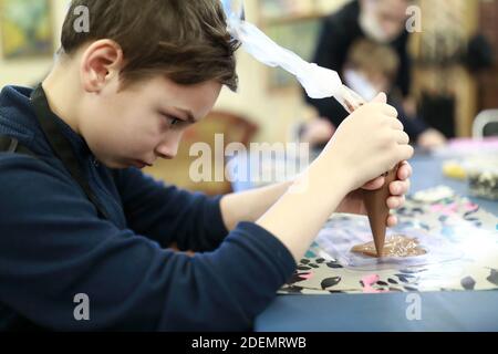 Portrait of boy Pouring Chocolate On Mold in workshop Stock Photo