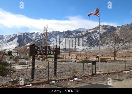 LEE VINING, CALIFORNIA, UNITED STATES - Nov 19, 2020: An American flag flies at the entrance to Mono Lake Cemetery with the Eastern Sierra mountain ra