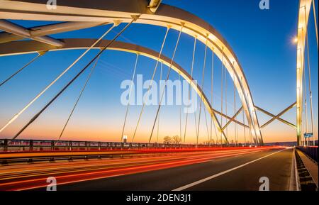 light traces of cars driving along the road at night through a beautiful modern highway bridge Stock Photo