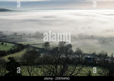 Glastonbury Tor, Somerset, UK. 26th November 2020. Stunning rolling mists and winter sunshine create an eerie atmosphere around Glastonbury and the So Stock Photo