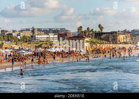 Lots of tourists and locals are swimming at blue Mediterranean sea and spending their vacation at the beach with background of Old Jaffa city of Tel A Stock Photo