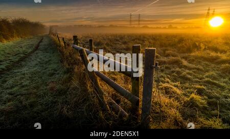 Frosty Frozen wooden fence with Autumn grassland and sunrise Stock Photo